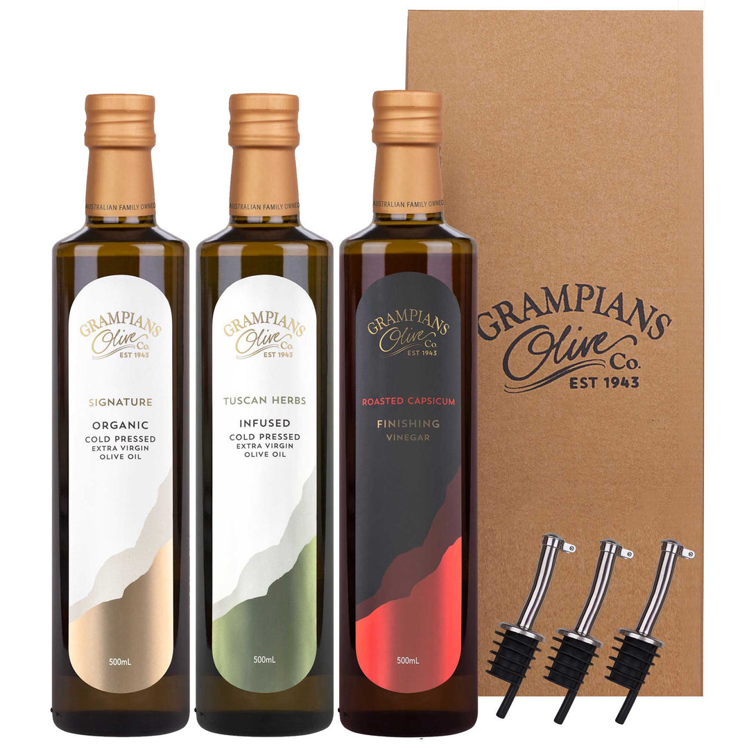 Three bottles gift set of Grampians Olive Co. olive oil and vinegar with a cardboard box and pourers on a white background.